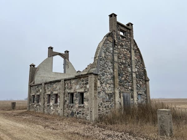 A barn built out of stone, that has lost its roof