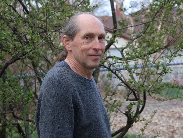 a man poses in front of a tree