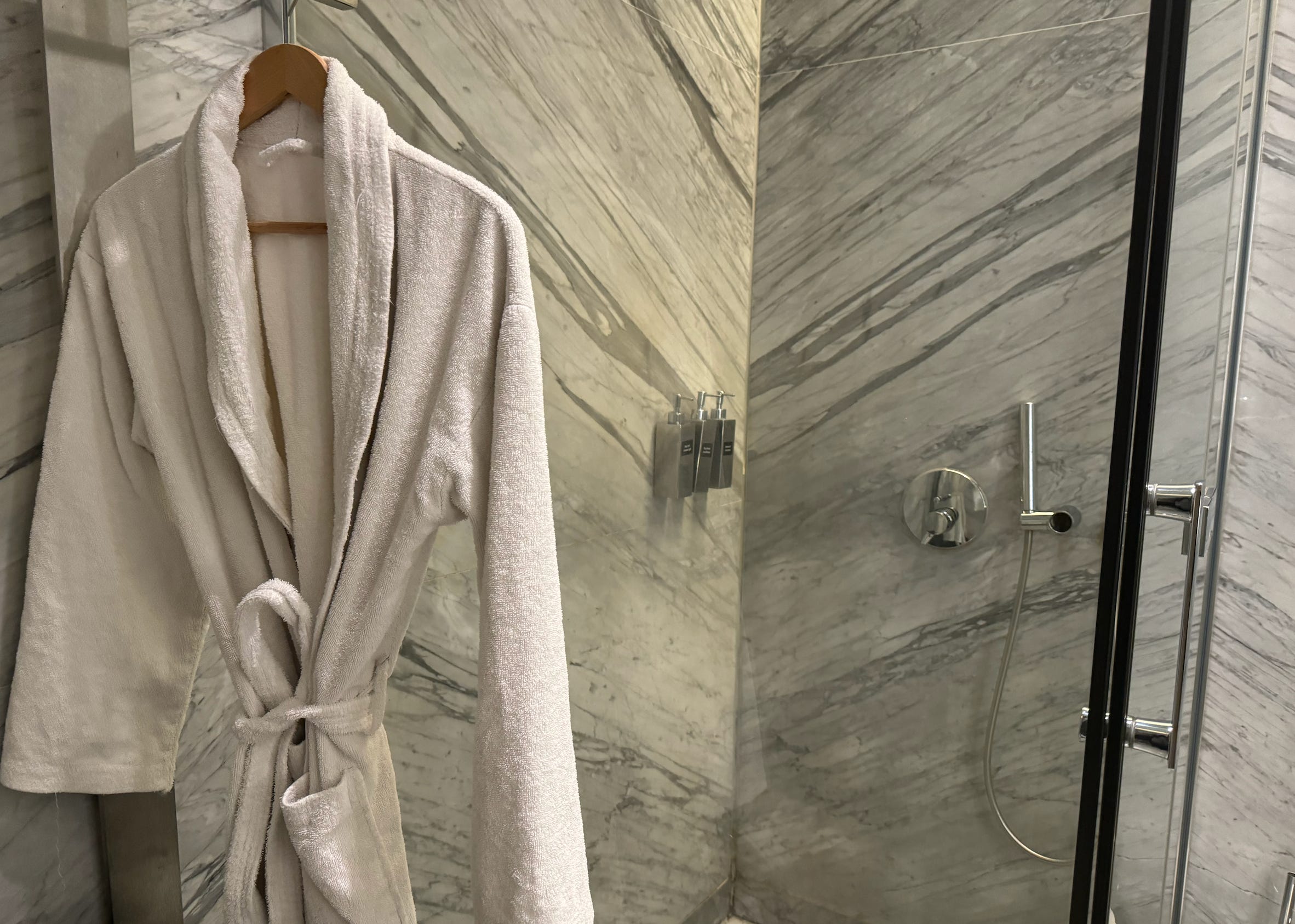 BAthrobe hanging outside of marble shower stall 