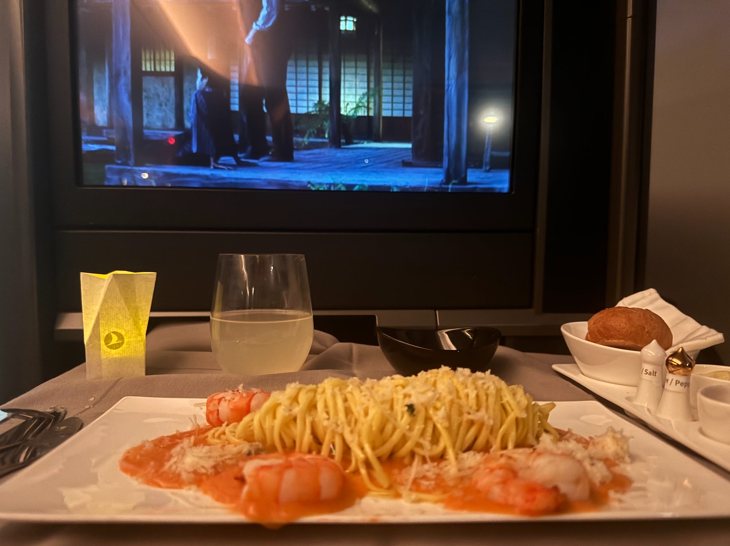 seafood pasta on Turkish Airline flights in front of screen playing a movie 