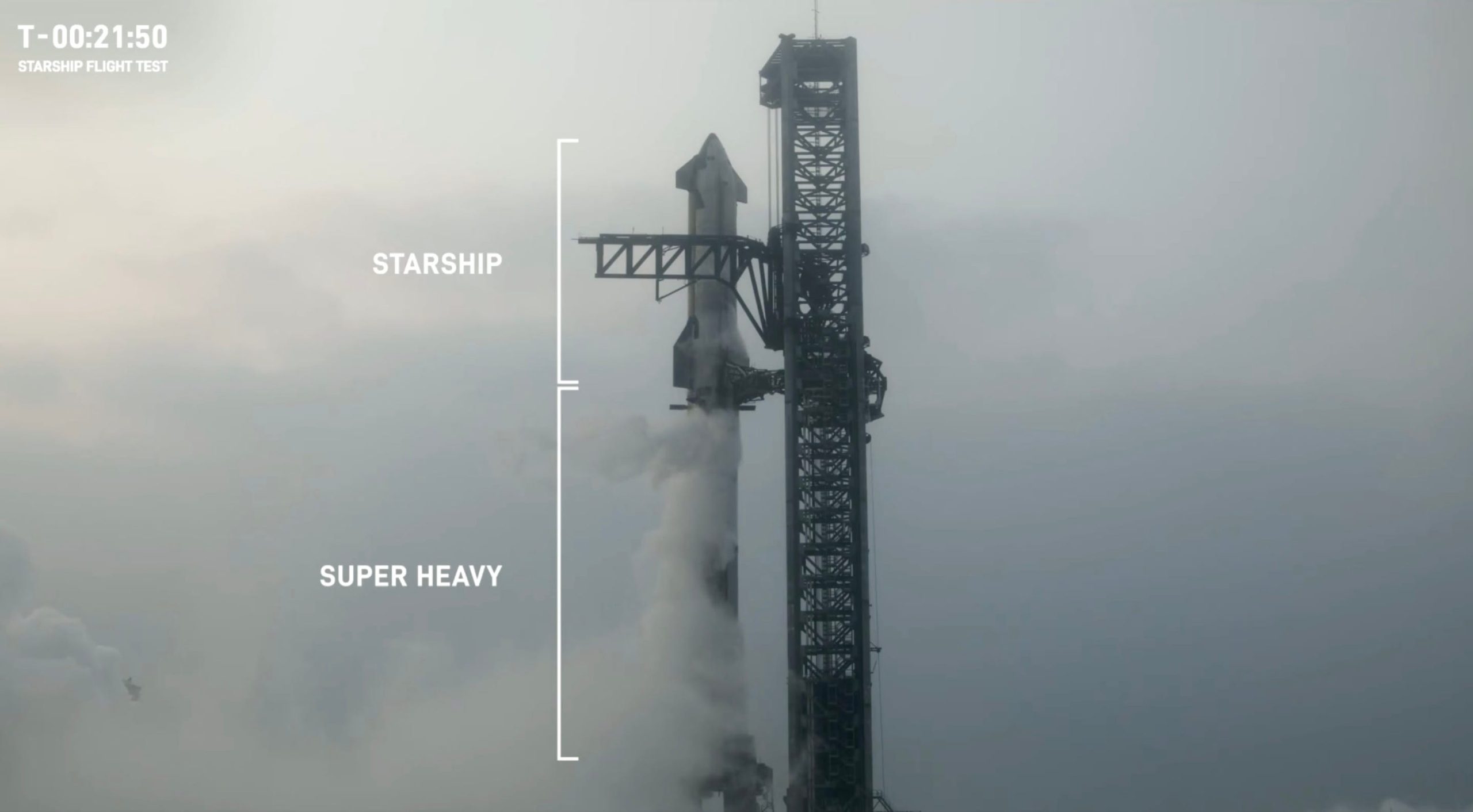 starship super heavy rocket tall black on a foggy launchpad next to black launch tower