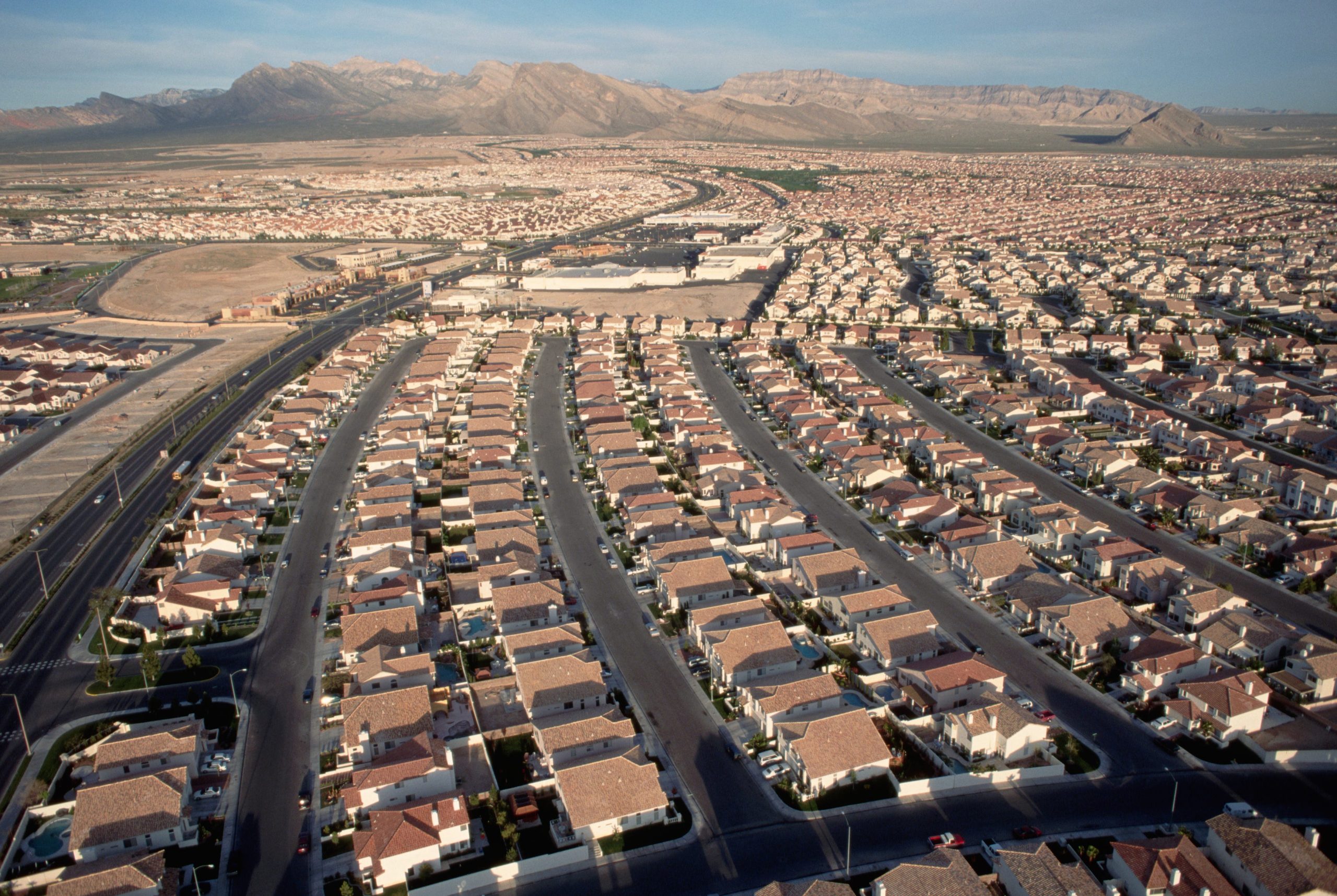 Rows of identical homes with uniform driveways and streets stretch towards the desert