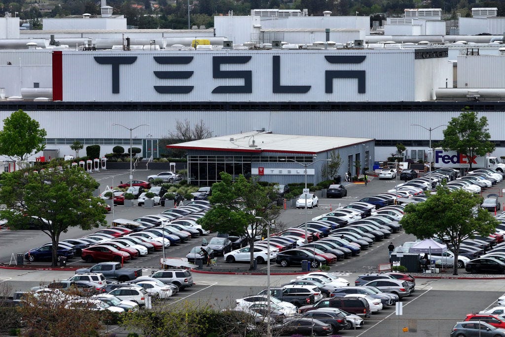 A parking lot in front of a large building with the Tesla logo on the side.