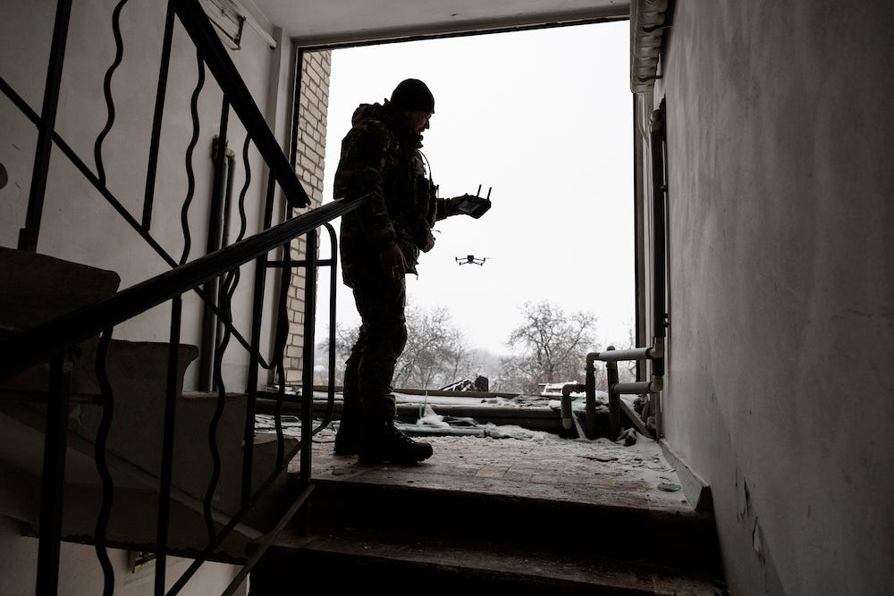 A drone operator with the Ukrainian Army's 93rd Brigade is seen silhouetted against a white sky as he launches a DJI Mavic 3 drone from a stairwell near the frontline with Russian troops on February 18, 2023 in Bakhmut, Ukraine.