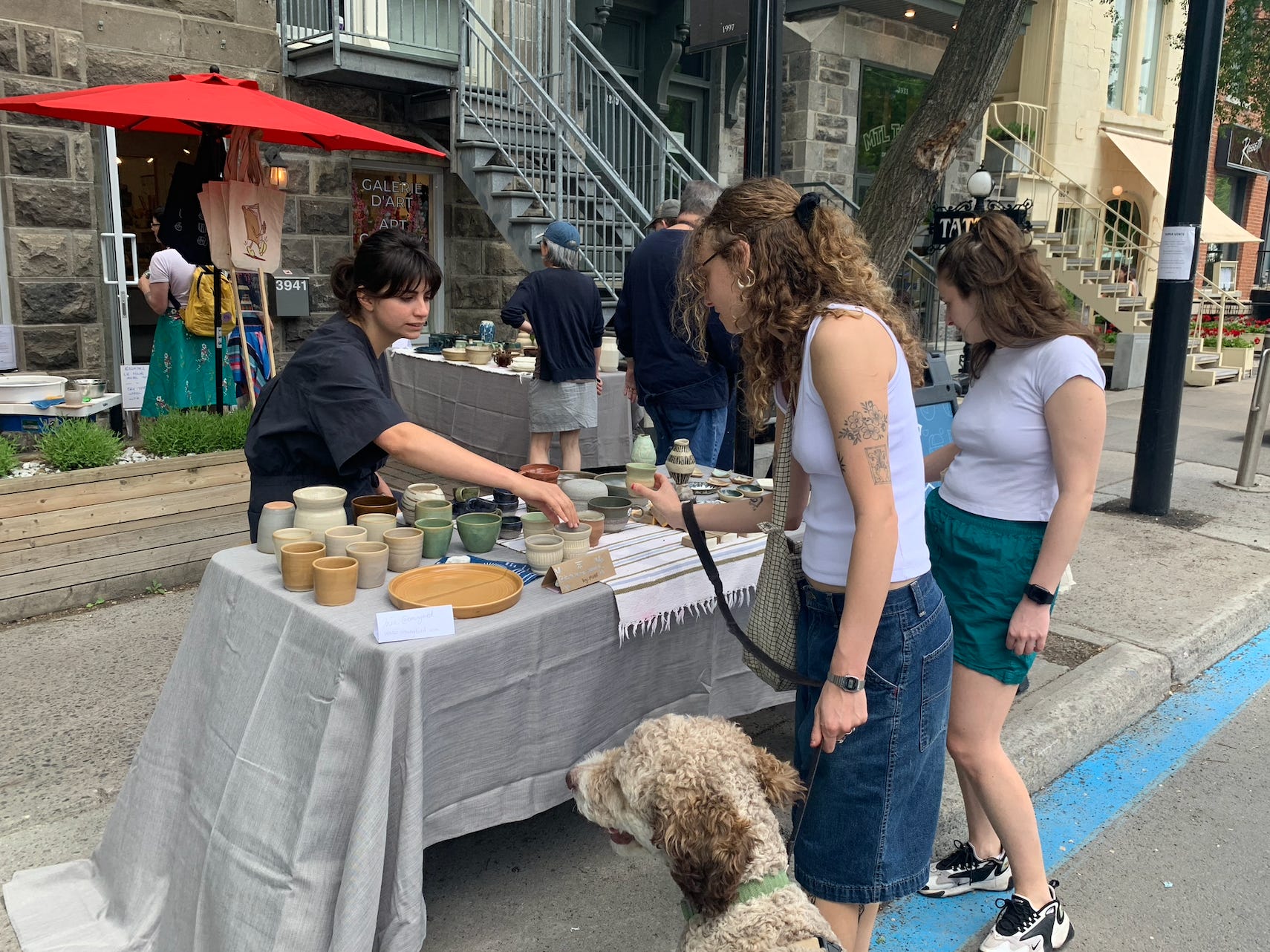 people perusing a pottery table outside a local business in montreal