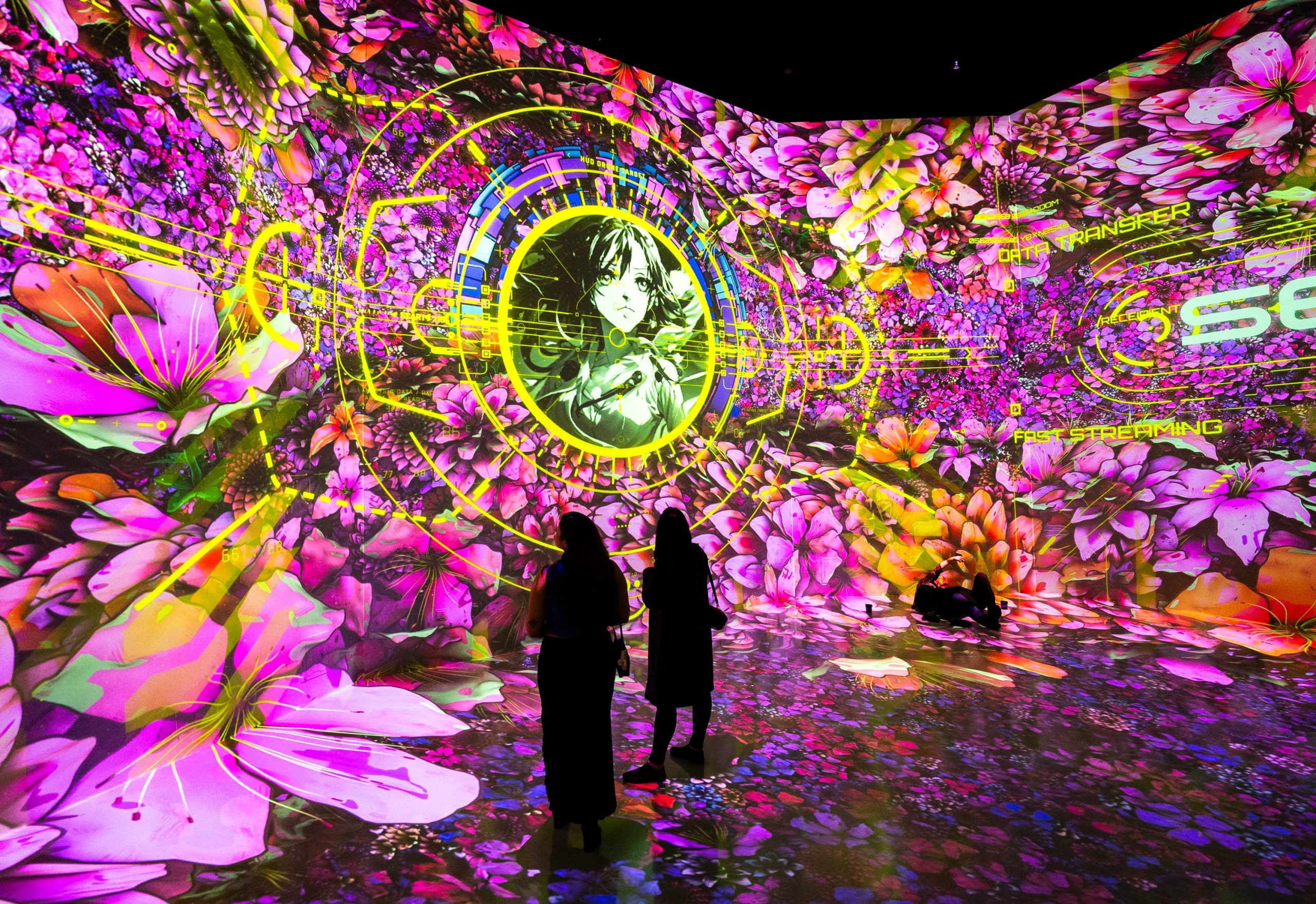 people stand in a digital immersive art piece showcasing virtual cherry blossoms