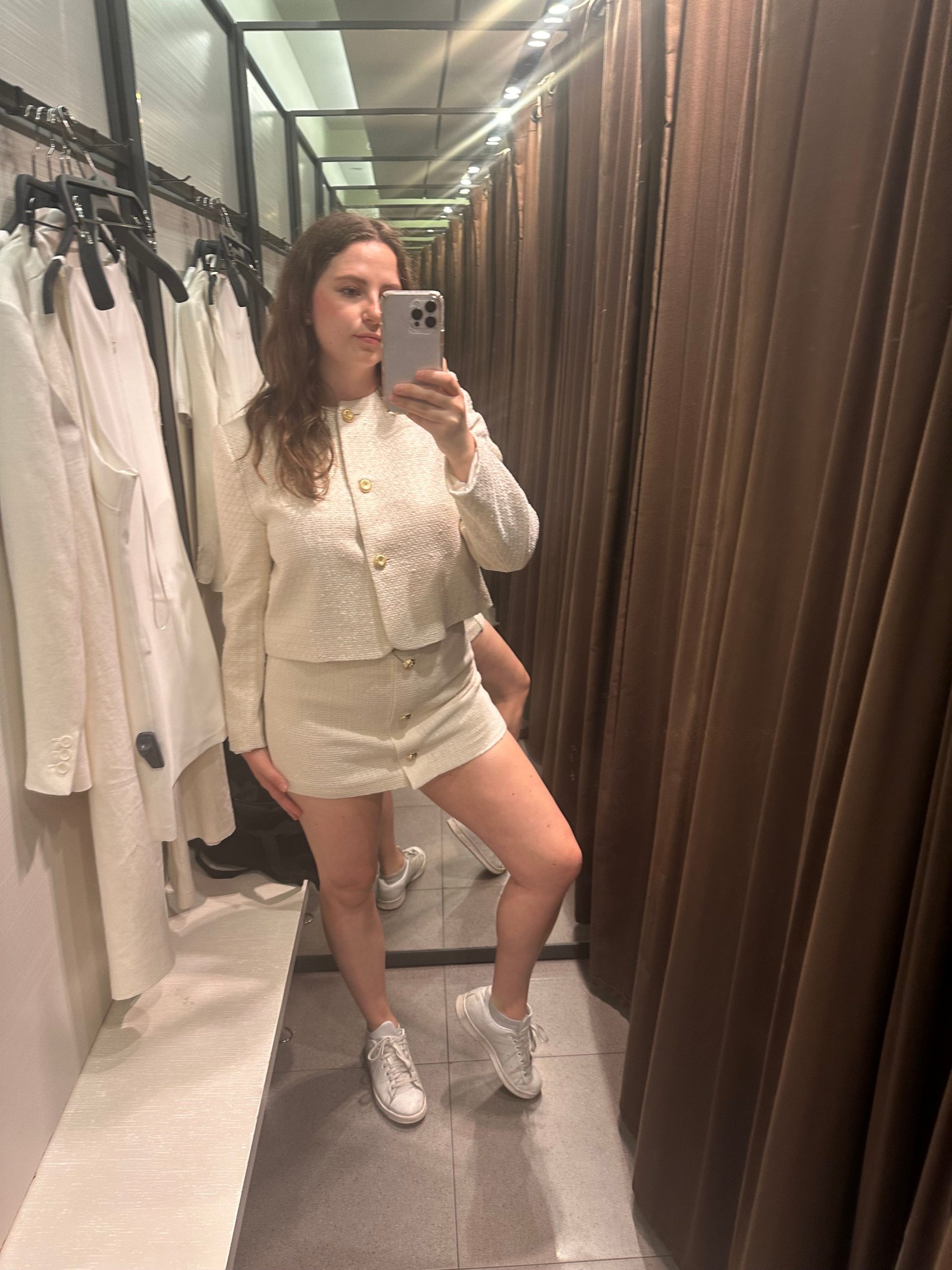 A woman takes a mirror selfie in a dressing room.