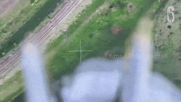 A 10-second video showing the view from a Russian FPV drone as it hovers, in a green landscape with tracks, above a small quadcopter drone in the air, that the videomaker identifies as Ukrainian. A net drops into view, from the upper drone, and takes down the lower one. Video uploaded April 27, 2024.