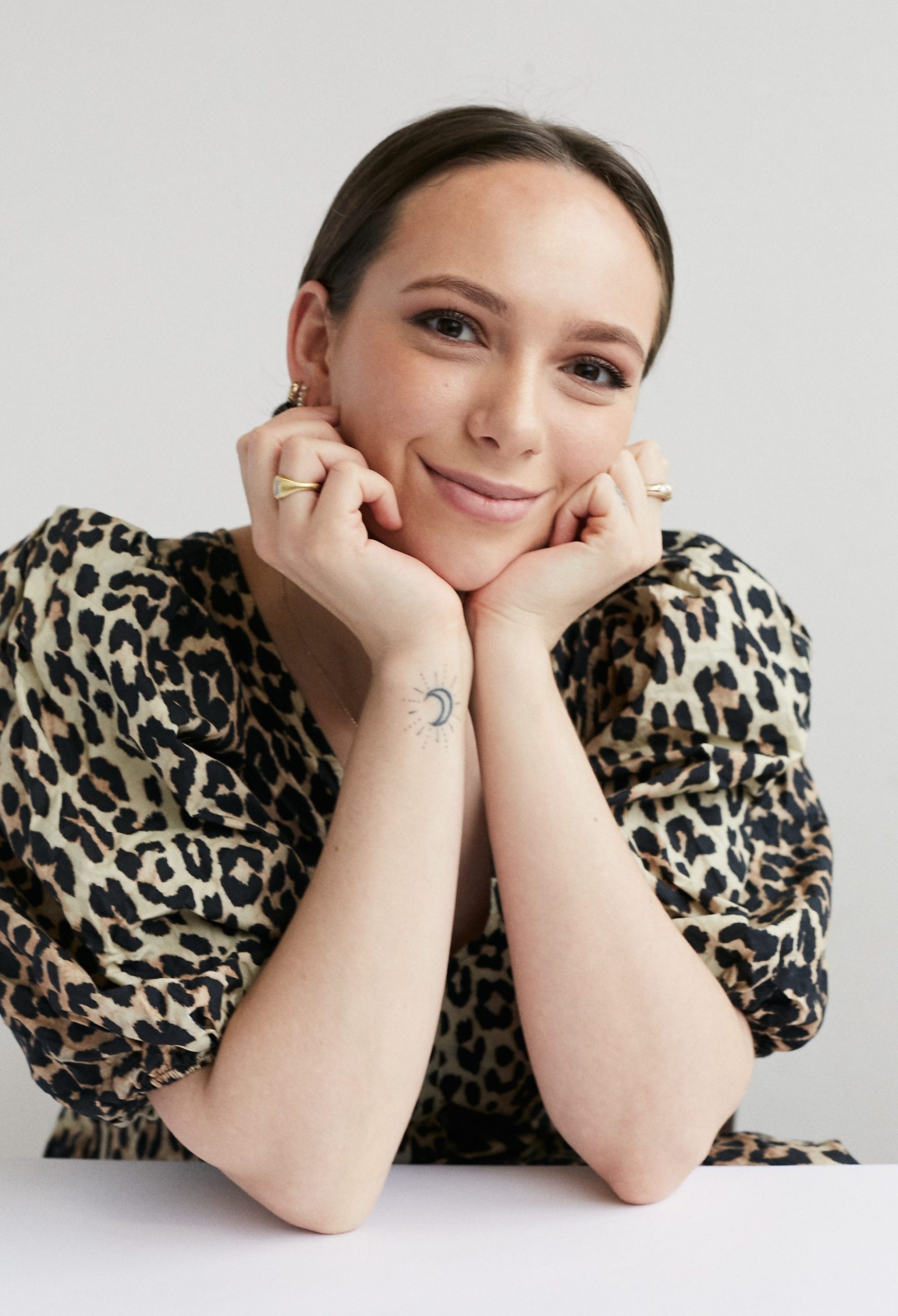 A woman leans her elbows on a table and smiles.