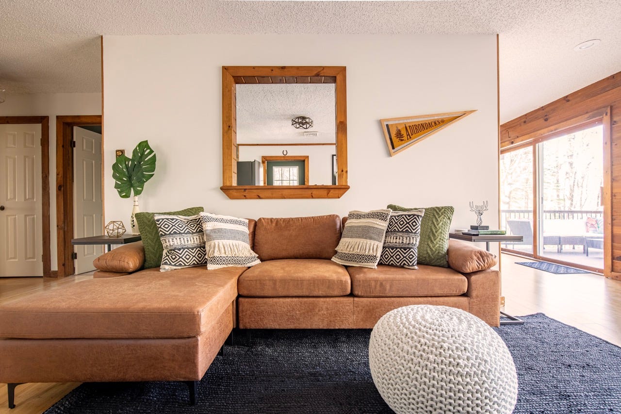 Brown leather sectional with mirror above it 