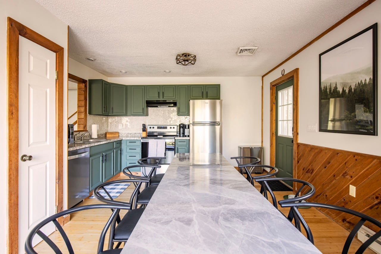 Green kitchen cabinets and white marble table in home 