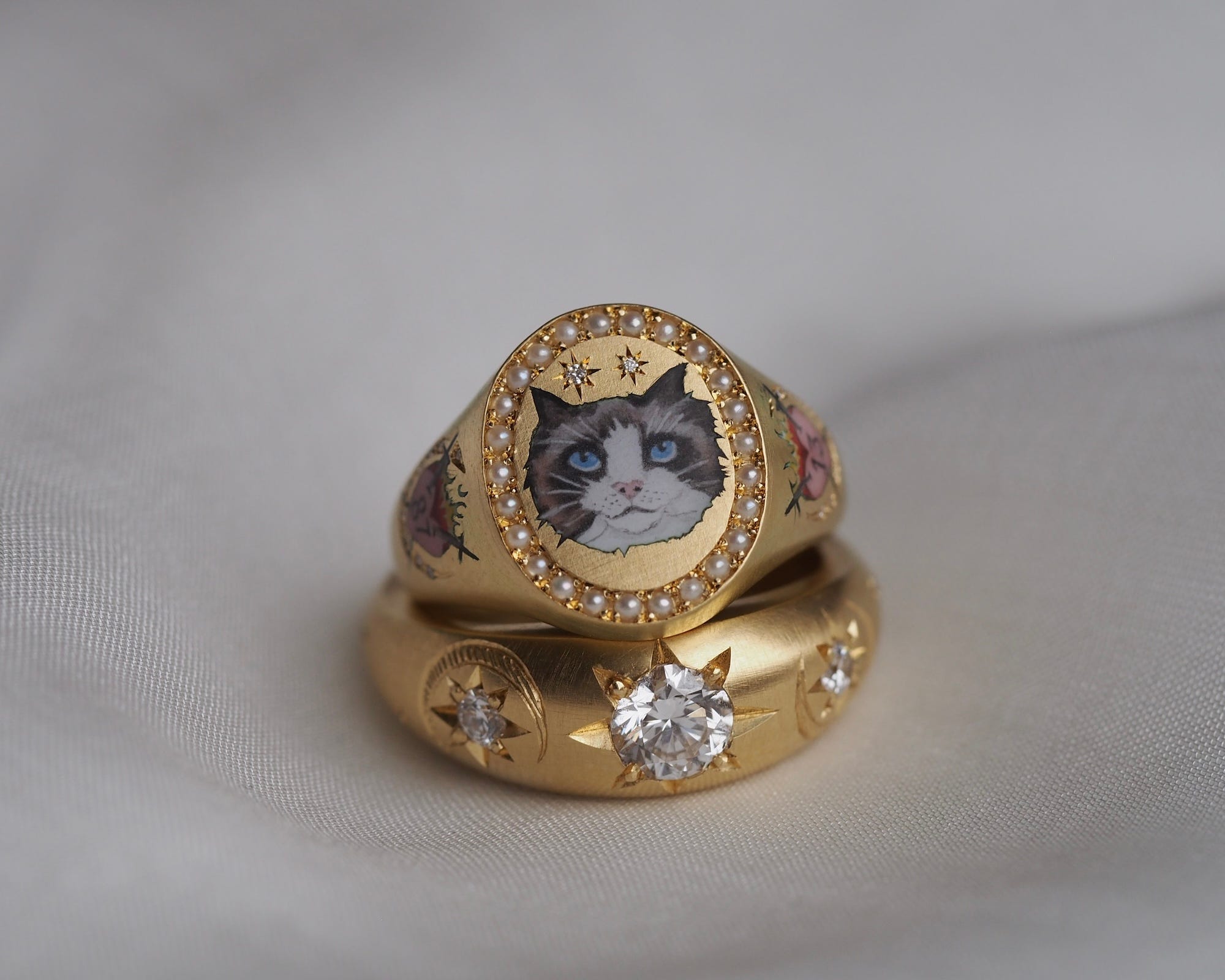 A gold ring with a painting of a cat in it.