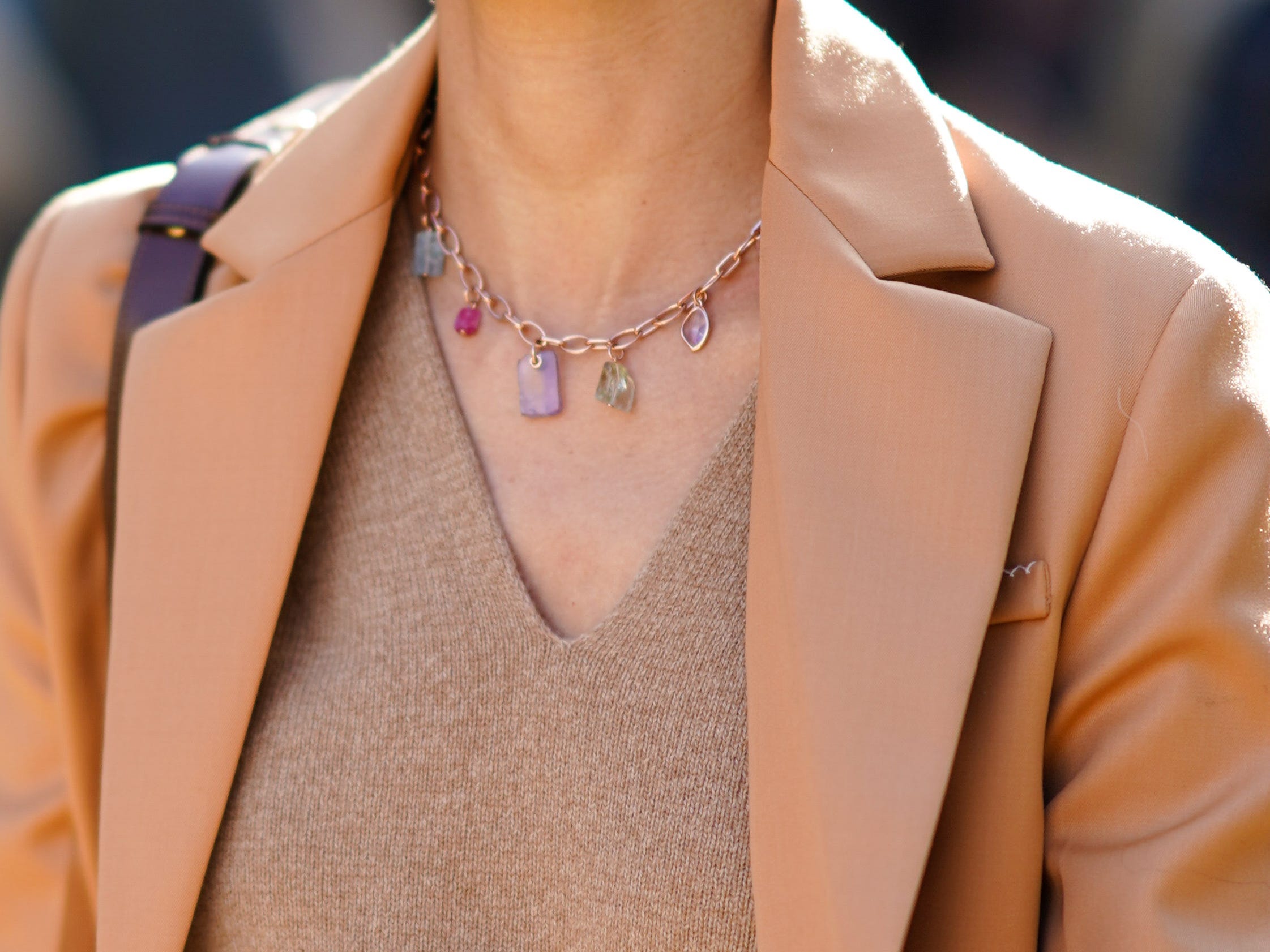 woman walking down a street wearing a neutral toned outfit with sunglasses and gold jewelry