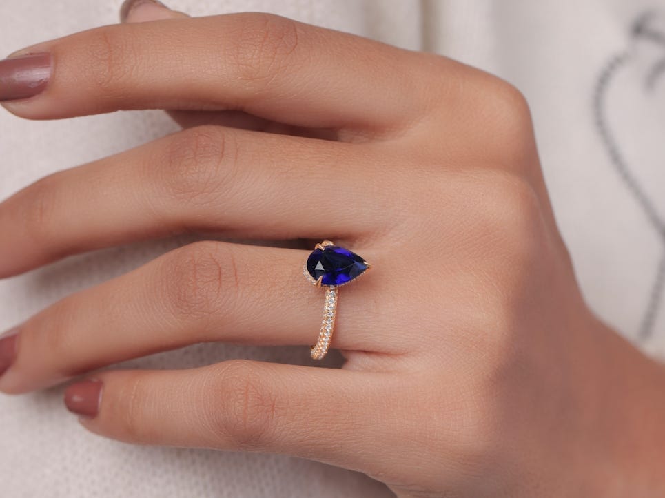 close up shot of a hand with a blue sapphire ring