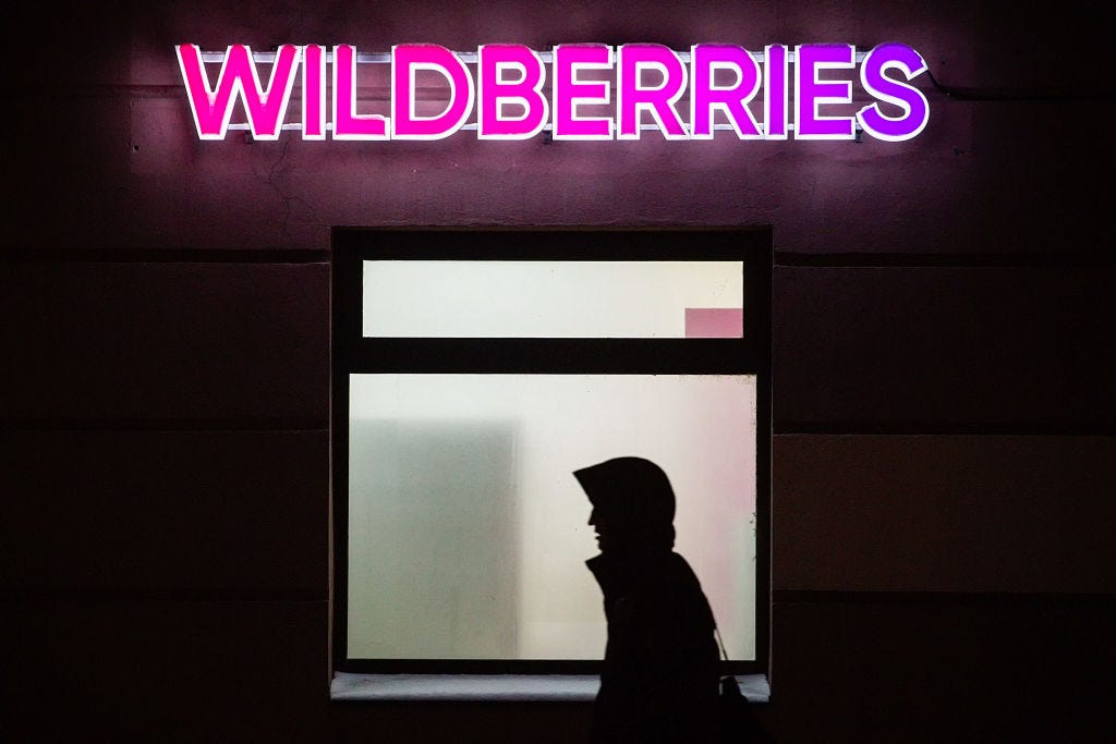 A man walks past a Wildberries delivery point at night