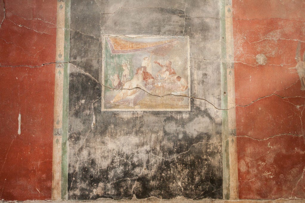 A cracked fresco known as Chaste Lovers on a crumbling black and red wall at Pompeii