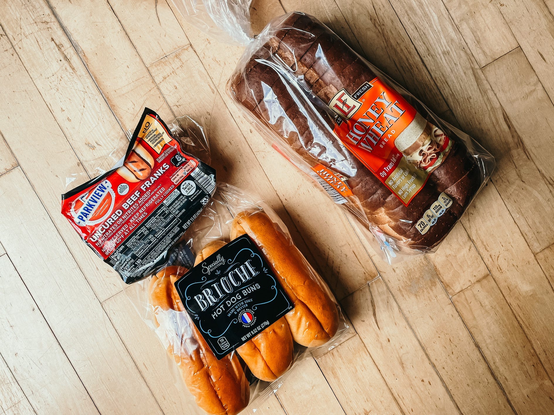 a pack of hot dogs, buns, and bread on a wooden surface