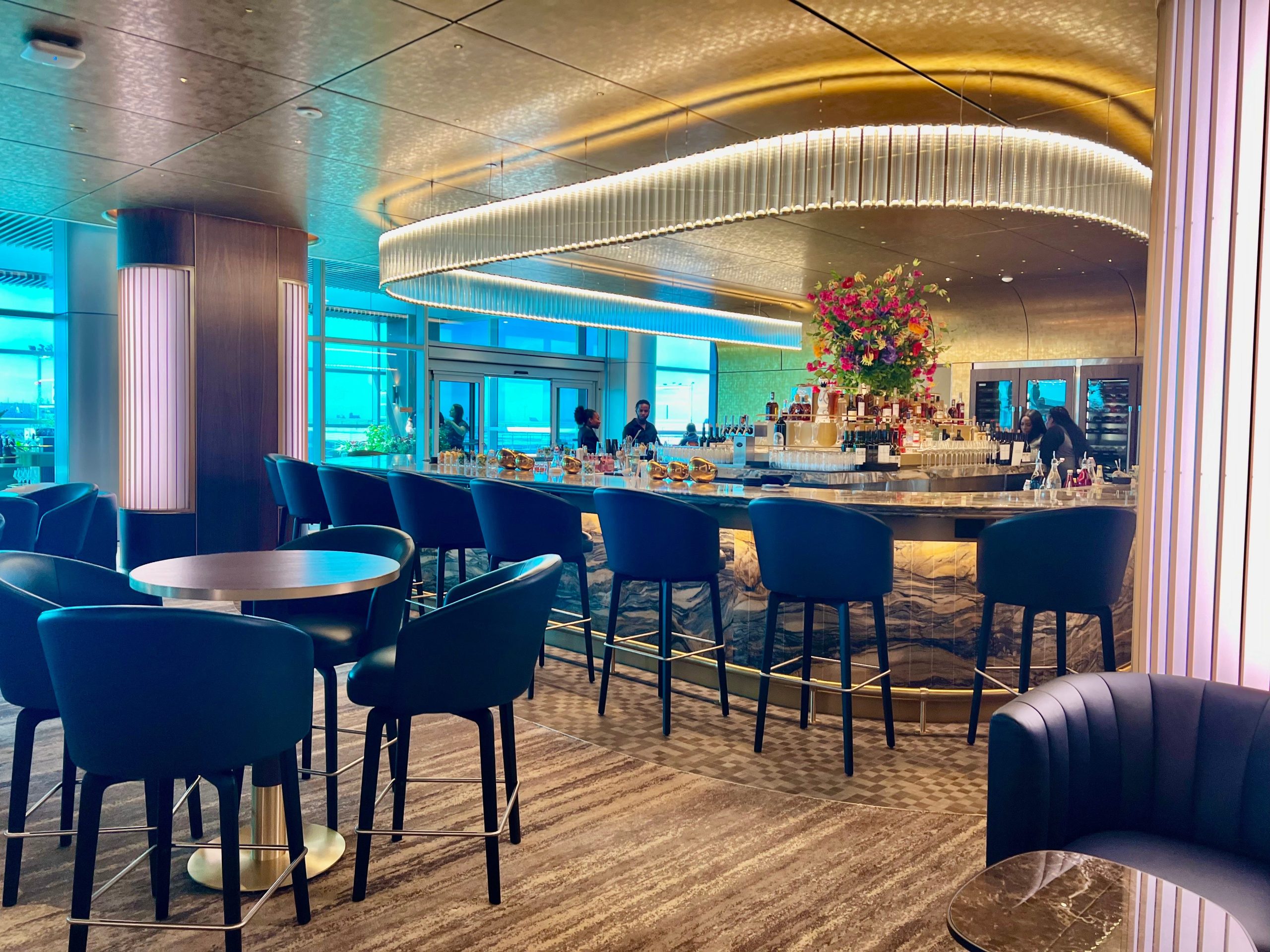 The bar with gold lighting and a flower bouquet in the middle. Top top chairs surround the half-circle bar.