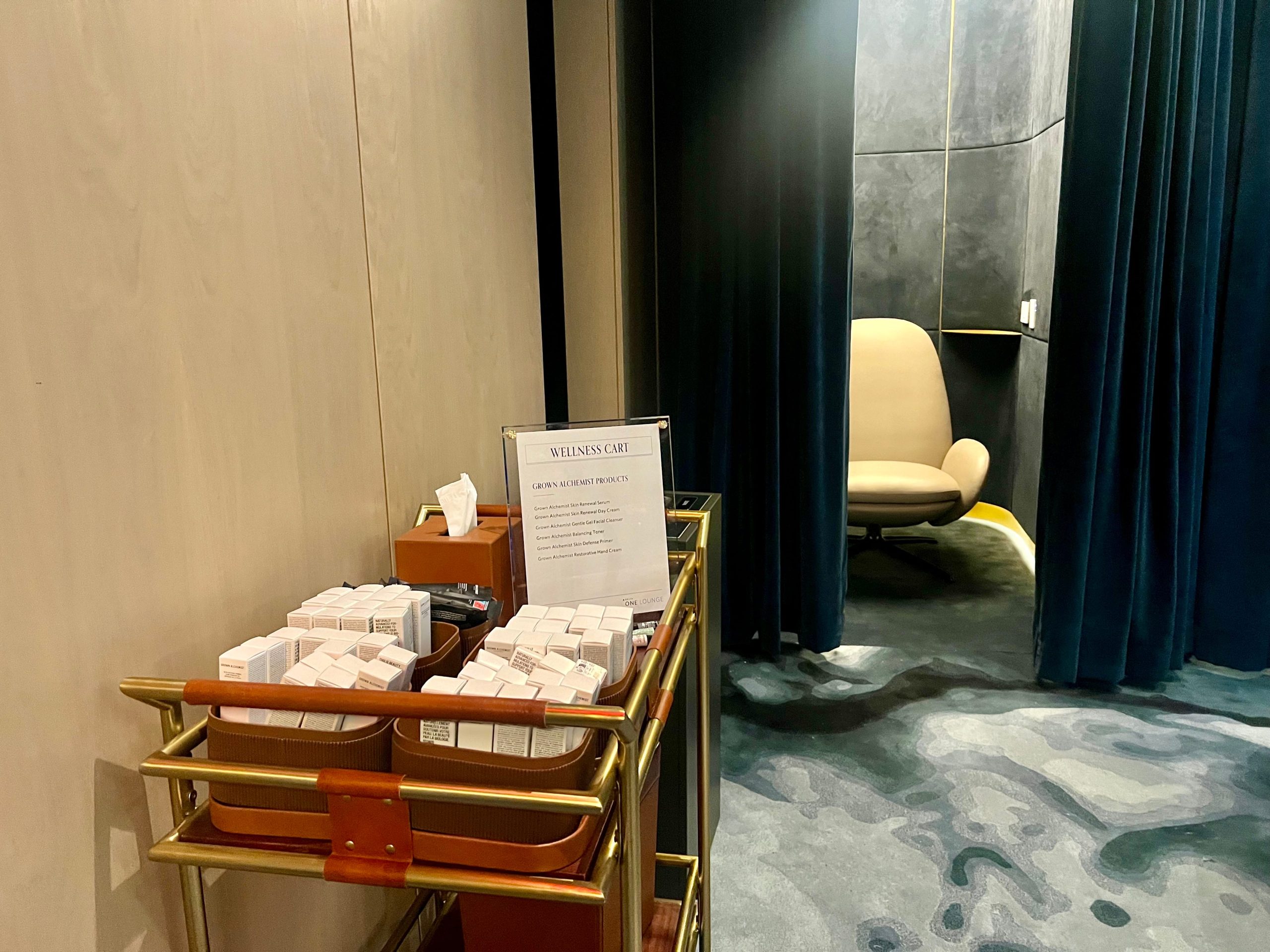 The wellness cart stocked with toiletries in front of the zero-gravity chair behind a blue curtain.