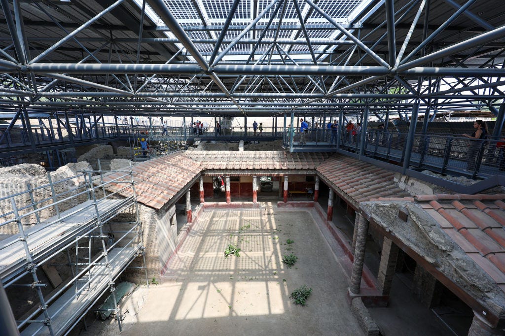 A public pedestrian pathway with people on it above of the Insula of the Chaste Lovers, in the archaeological excavations of Pompeii