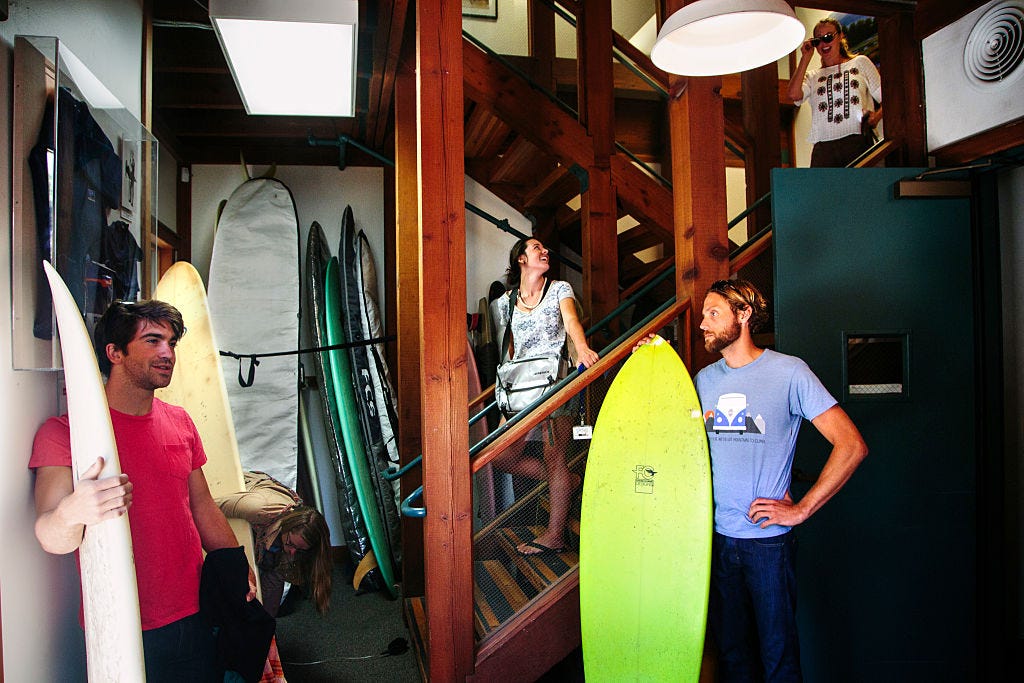 Evan Daniel, product designer, Tasha Woodworth, associate designer, and Paul Hendricks, brand responsibility analyst, grab surfboards stored at the Patagonia Corporate Headquarters during a lunch time surf break in Ventura, California on Friday, September 19, 2014.