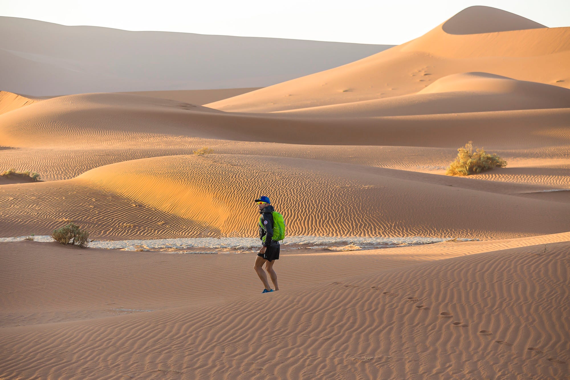 Ray Zahab in running attire walking in the namib desert with sand dunes all around him