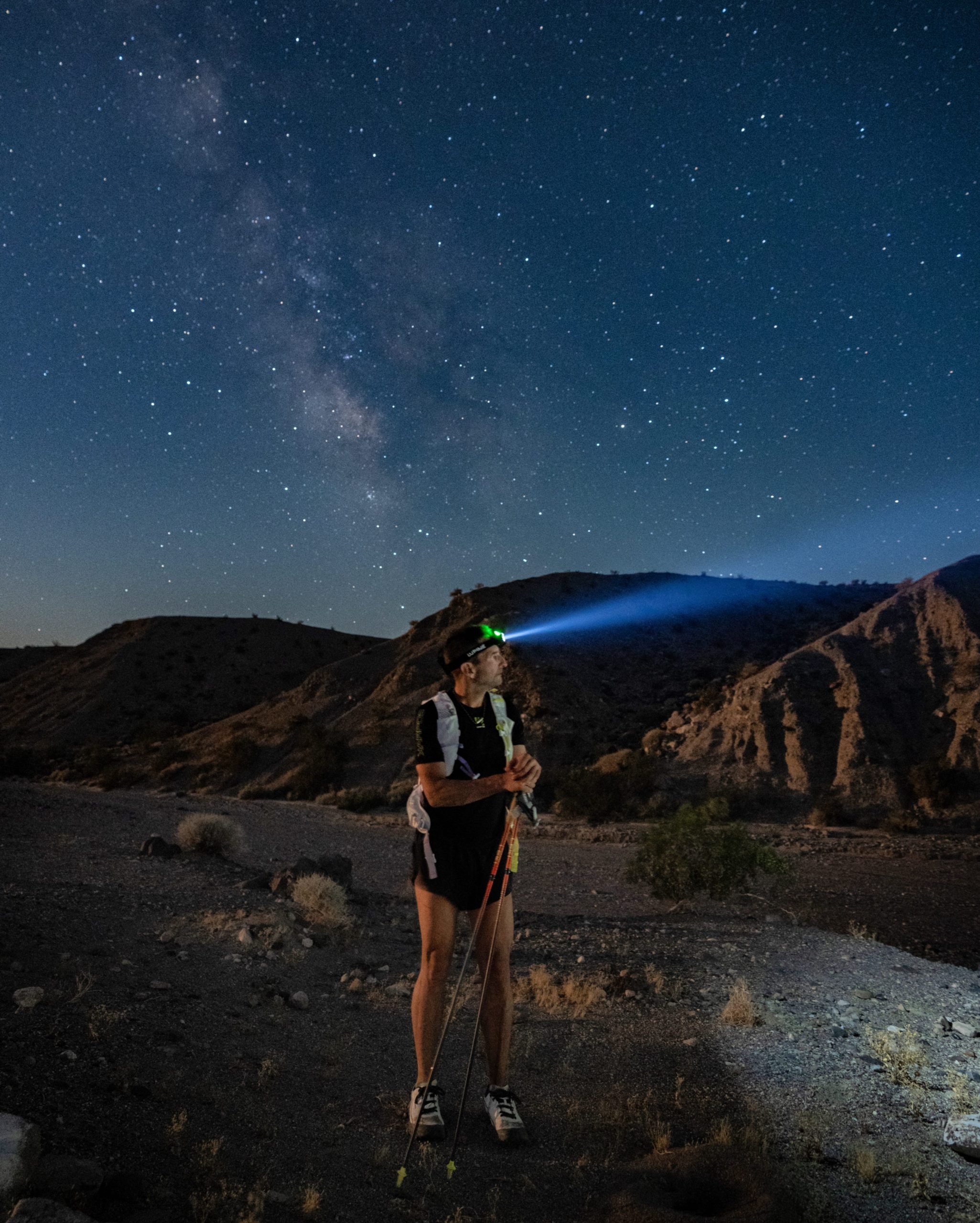 Ray Zahab standing in running attired in the middle of the desert at night with stars and the milky way galaxy in the background