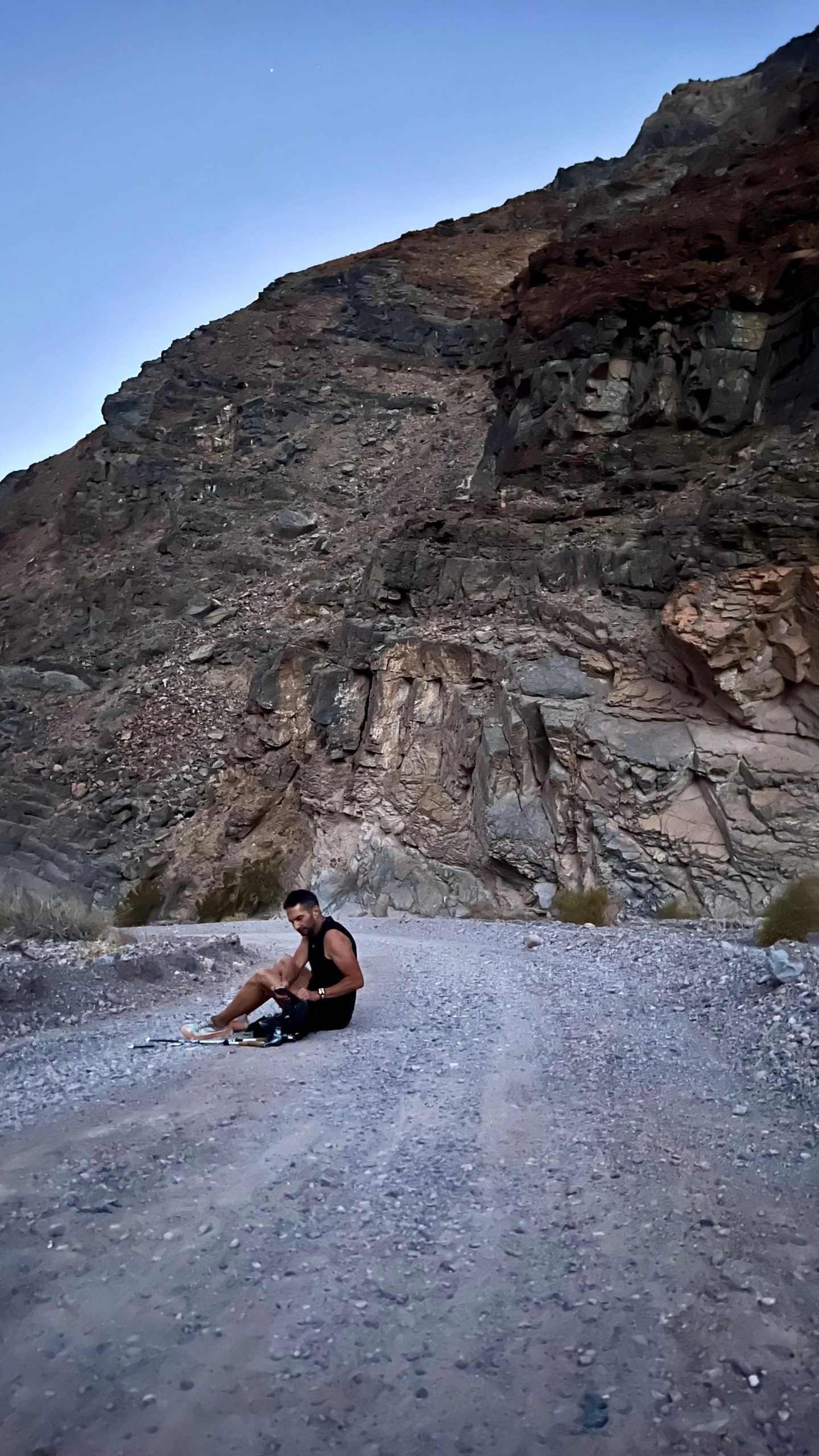 Ray Zahab sitting on gray gravel road in death valley