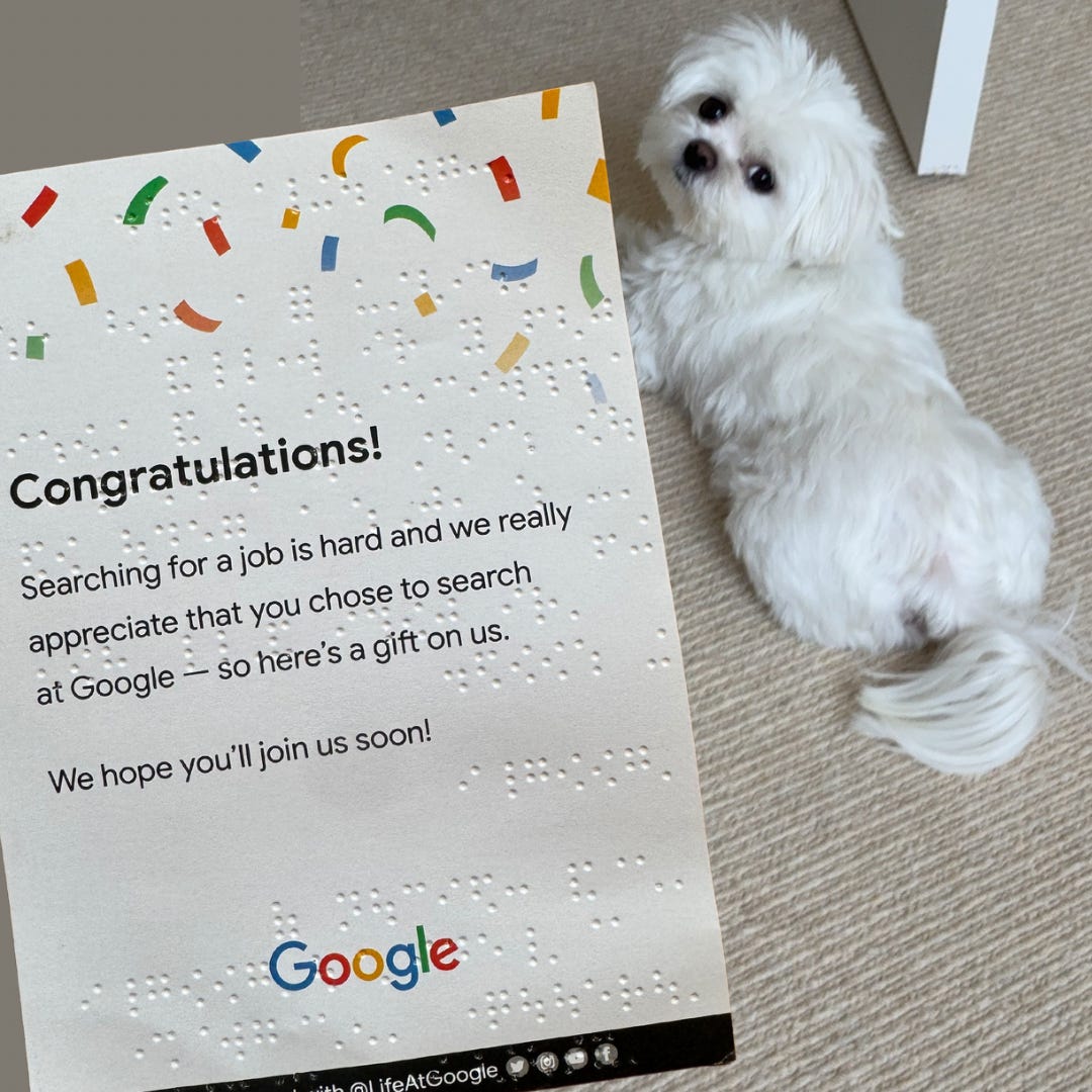 A photo of a congratulatory card from Google held up to the camera, with a white dog in the background