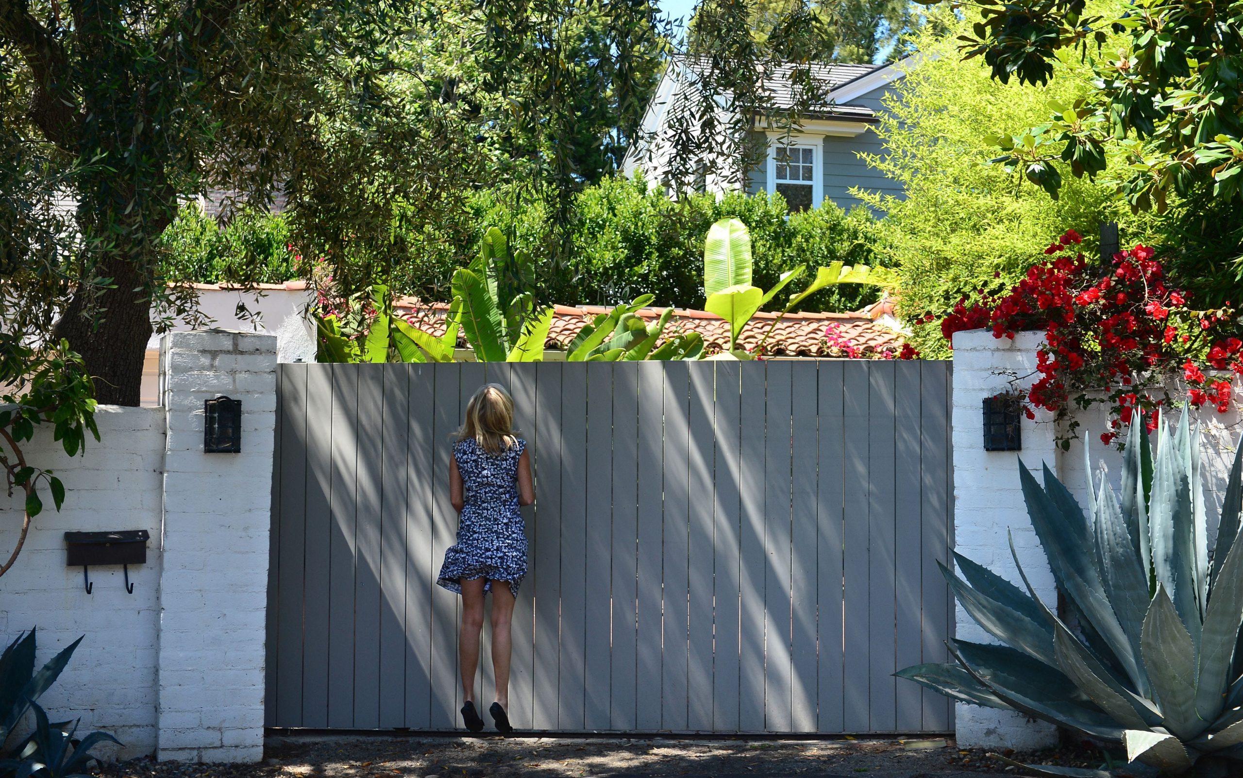 A woman jumps for a better view through the gate outside the house where Marilyn Monroe died in Brentwood, on July 28, 2012